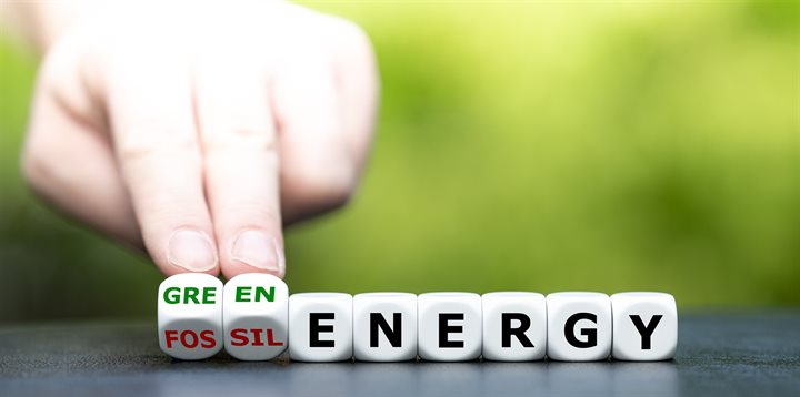 Hand draait dobbelstenen en verandert de uitdrukking fossiele energie in groene energie.