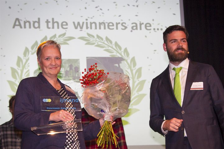 Annemarie Manger krijgt uit handen van bestuursvoorzitter Tim De Rudder de award overhandigd.
